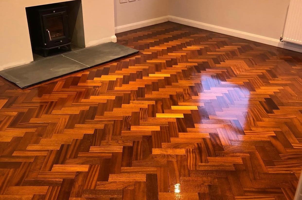Living room after Parquet Floor Repairs in West Kensington, showcasing a high-gloss finish on a rich oak herringbone parquet floor.