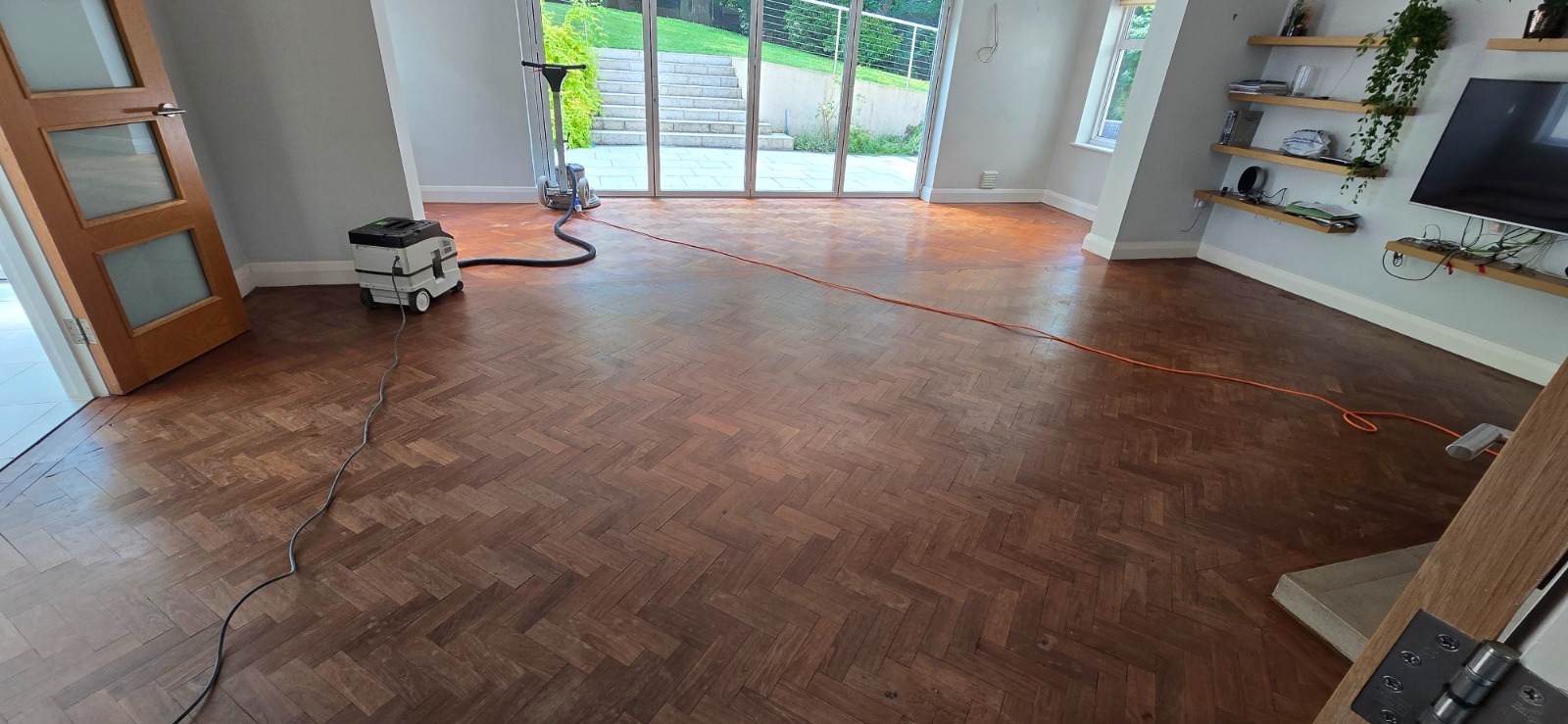 Parquet Floor Sanding in West Kensington – dark oak herringbone parquet living room floor prepared for dust-free sanding, with professional machines and cables in place.