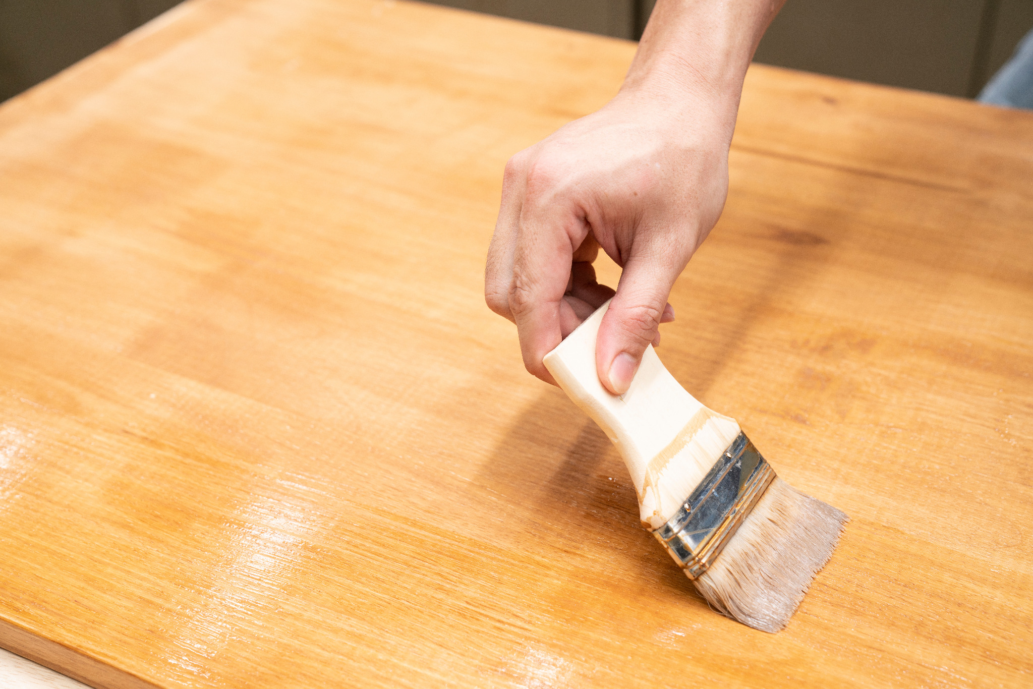Worktop Refinishing in West Kensington – close-up of clear finish being brushed onto a solid oak hardwood kitchen worktop above an oak plank wood floor