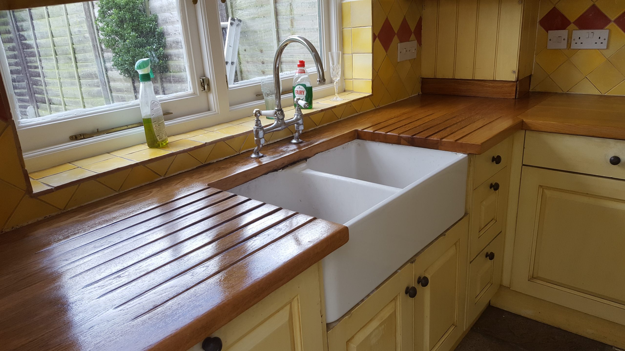 Worktop Refinishing in West Kensington – restored solid oak wooden kitchen worktop around Belfast sink with natural stone tile floor